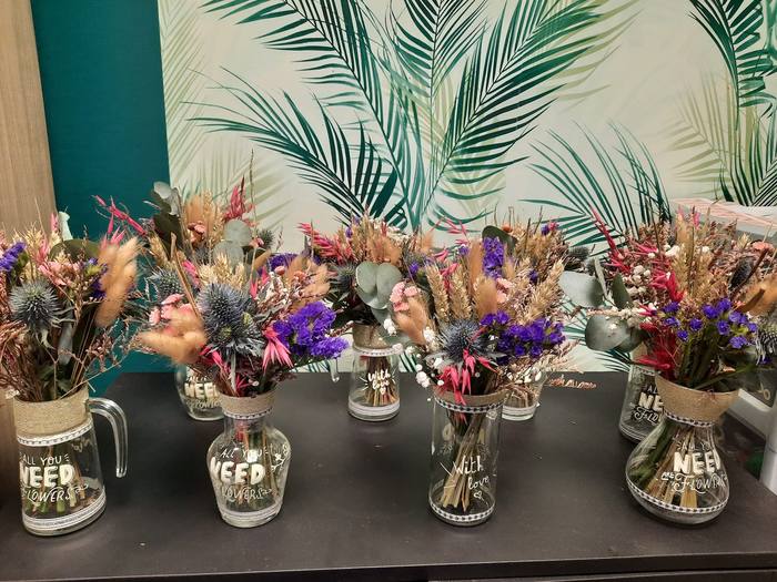 Bouquets de fleurs séchées présentés dans des vases décorés « All you need are flowers »