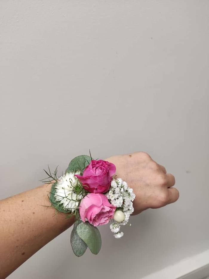 Bracelet floral aux roses roses et gypsophile porté au poignet